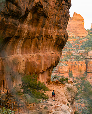 Hiker surrounded by large red rocks on cliffs