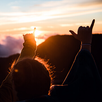Silhouettes of people hands shaka sign