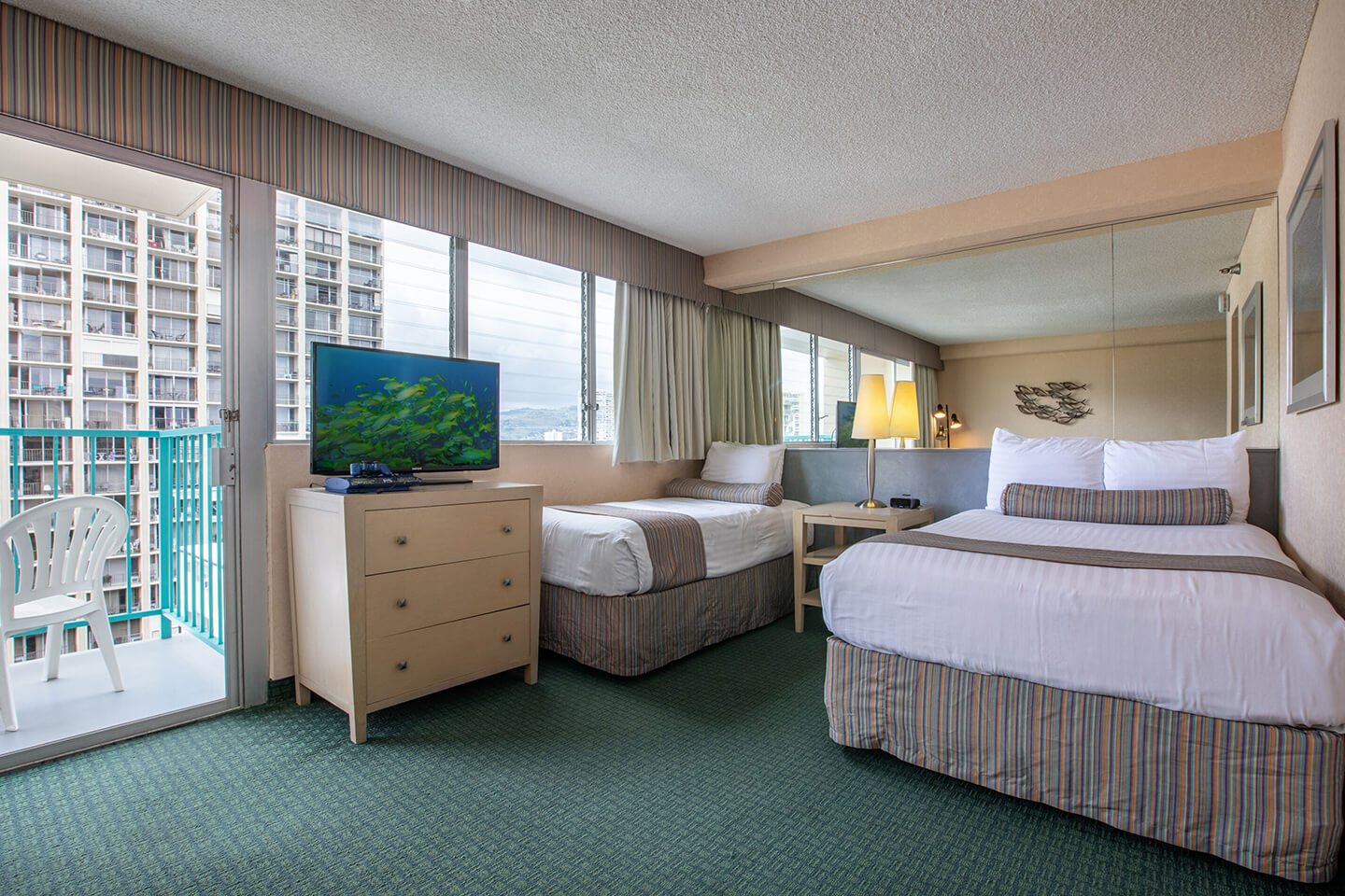 Room with 3 beds, a TV. and balcony.
