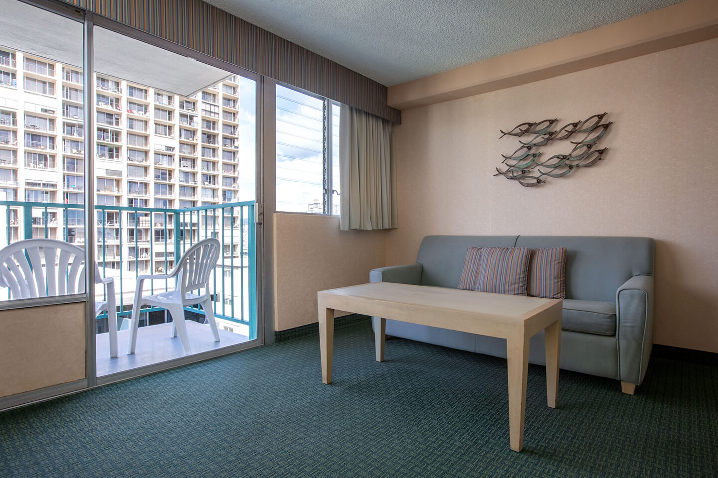 Living area with a sofa and coffee table, TV, and balcony.