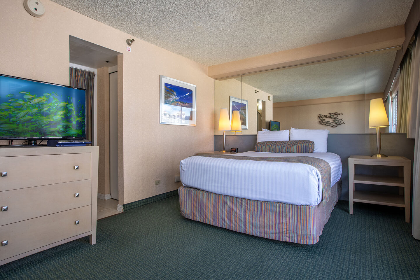 Room with a bed, TV and dresser.