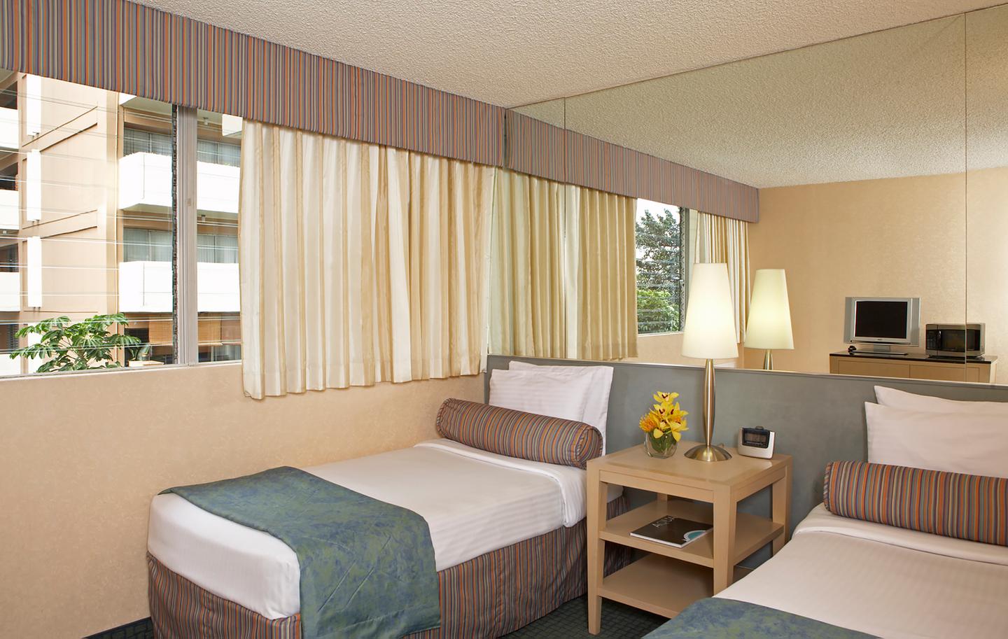 Room with 2 beds, lamp, nightstand, and large window.