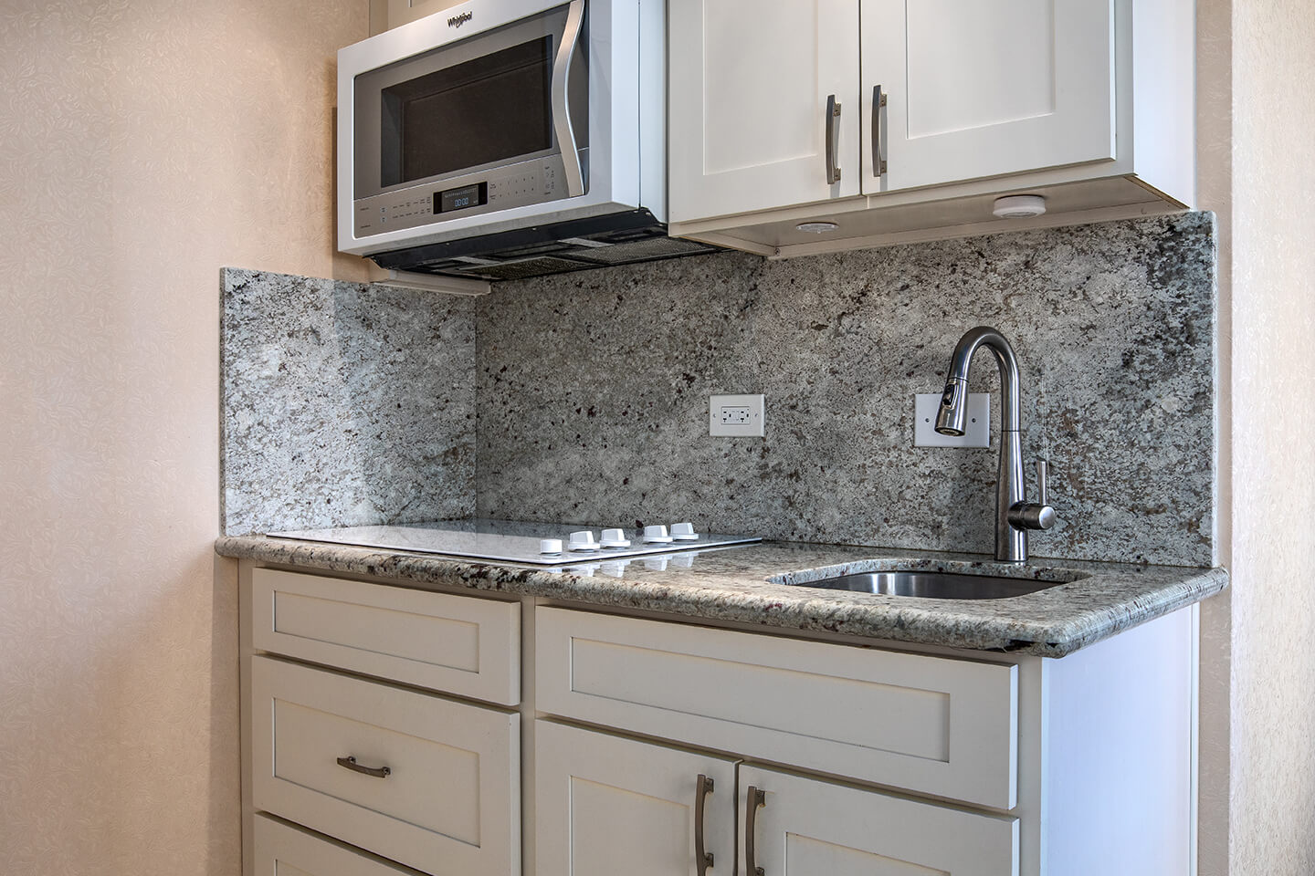 Kitchenette with a microwave, sink, and stovetop.