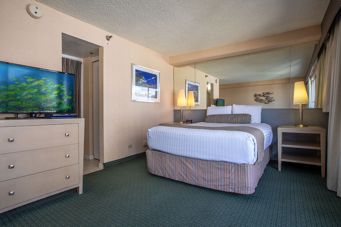 Room with a bed, TV, dresser, and entrance to bathroom.