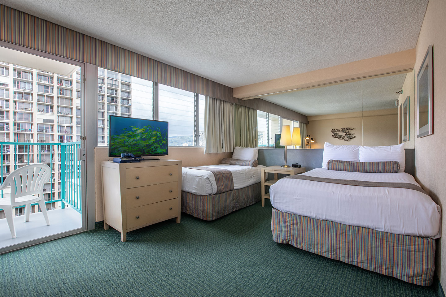 Room with 2 beds, TV, dresser, and balcony.