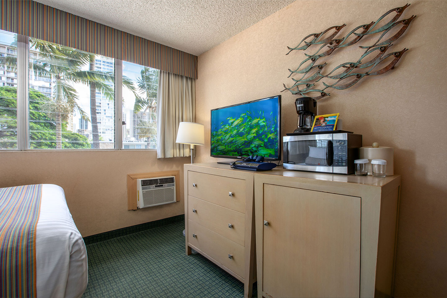 Room with large window and a TV, dresser, coffee maker, and microwave.