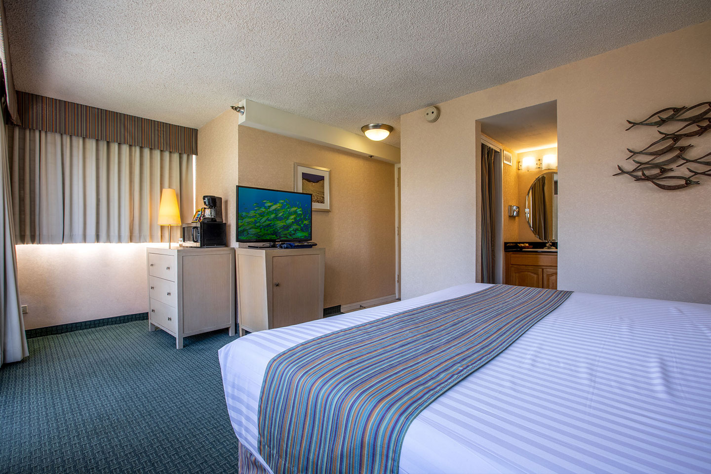 Room with a bed, TV, dresser, and entrance to bathroom.