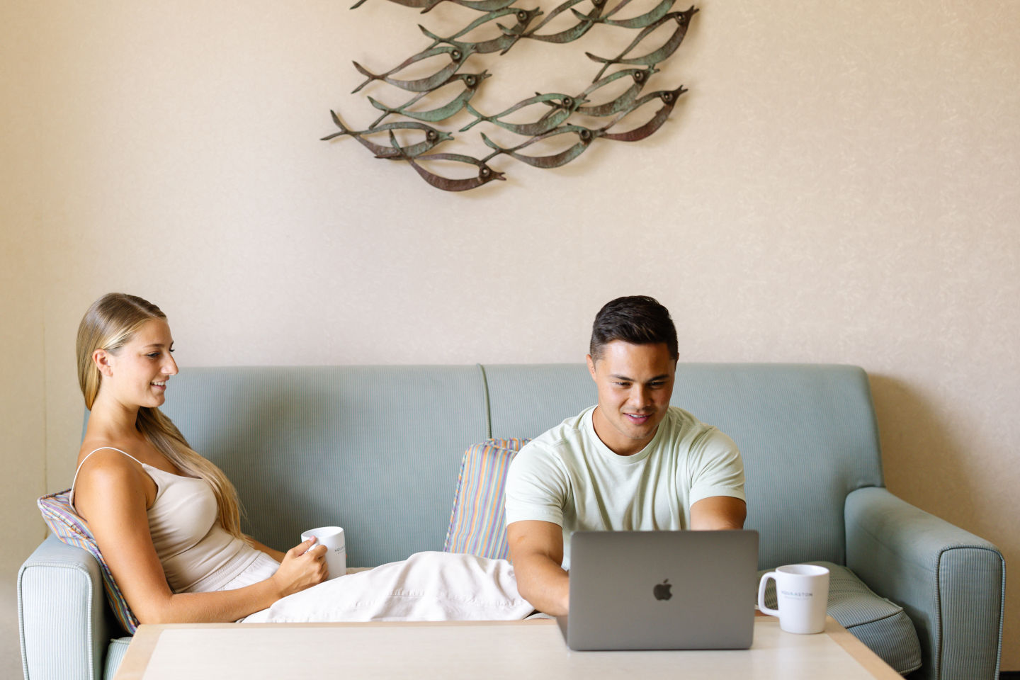 Man using laptop computer and woman relaxing on sofa.