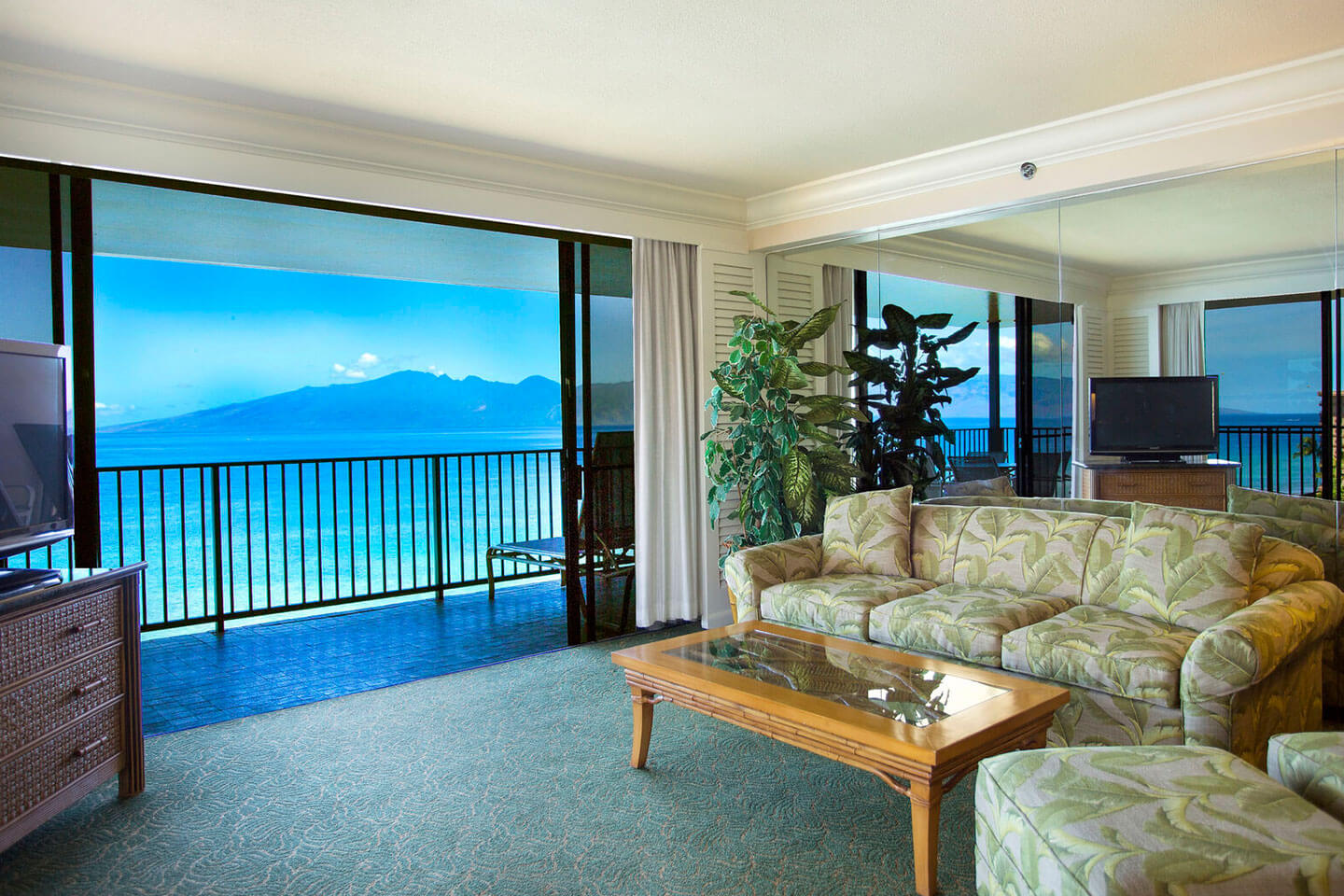 Living area with a couch, coffee table, TV, and balcony with ocean views.