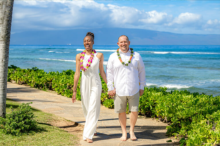 Newly wed couple walking on oceanfront lawns