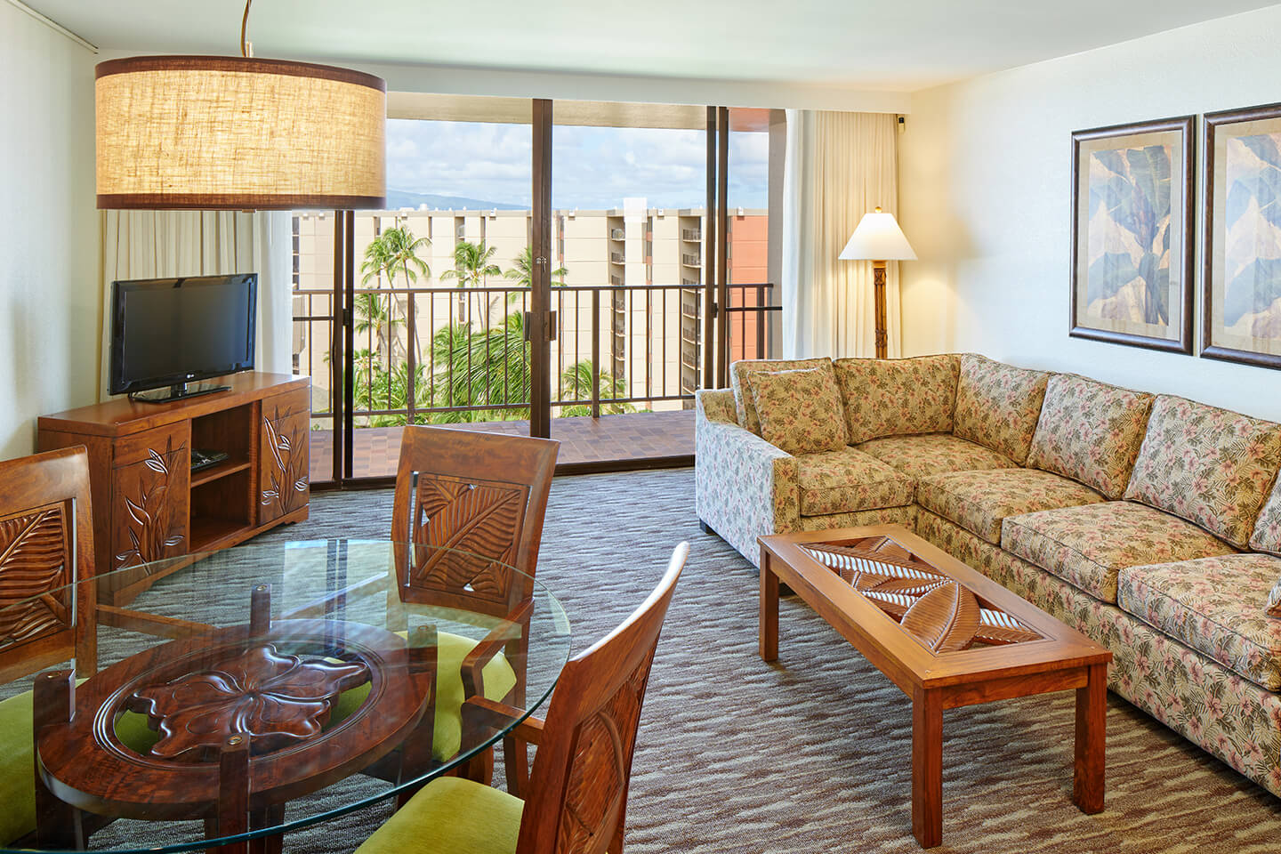 Living area with a couch, coffee table, TV, dining area, and balcony.