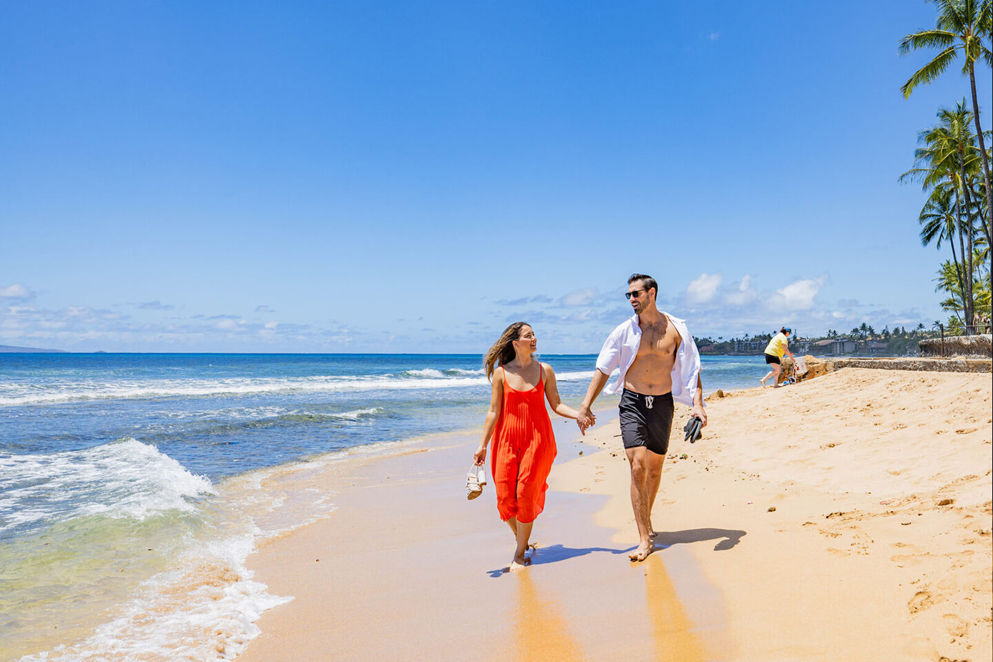 Couple waking along sandy beach.