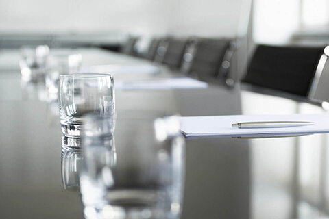 Table with glassware, pen, paper, and chairs.