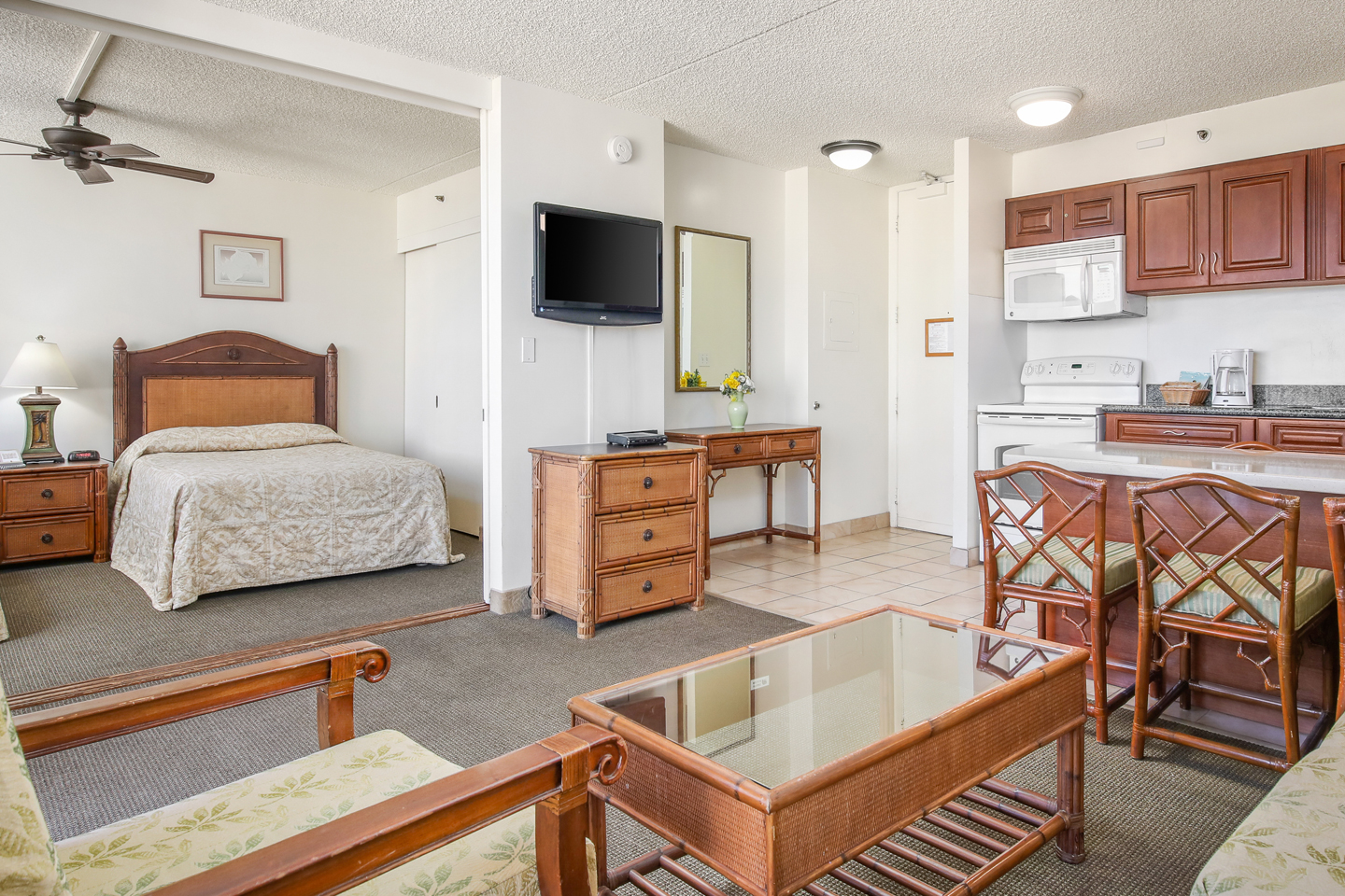 Living area with a bed, couch, coffee table, TV, and balcony.
