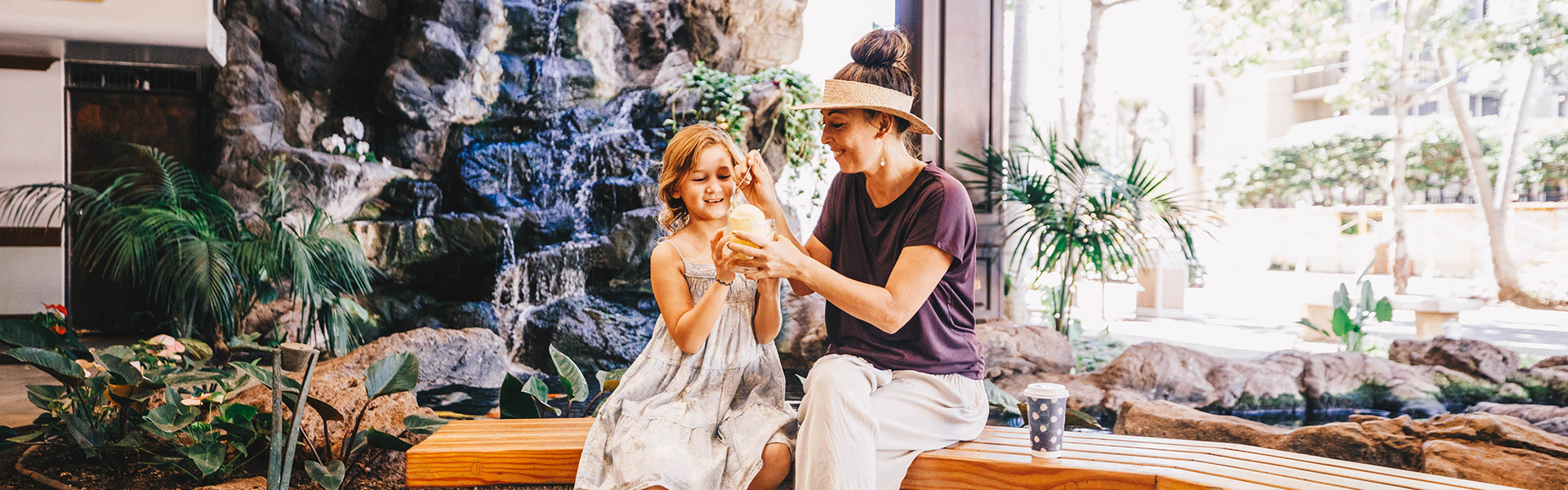 Daughter and mother eating frozen desert on bench in lobby area