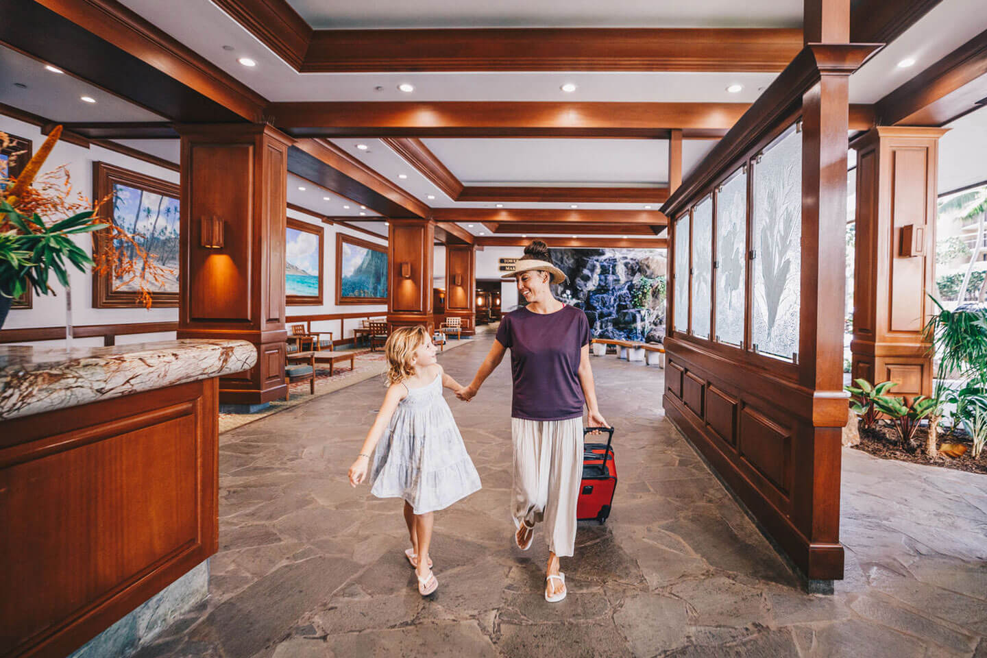 Mother and daughter walking through hotel lobby.