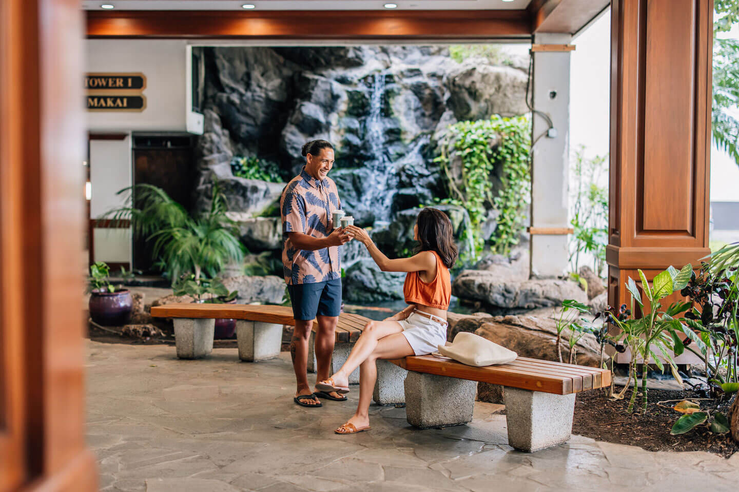 Couple having coffee in lobby near water feature.