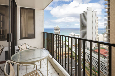 Balcony with chairs and table, view of ocean.