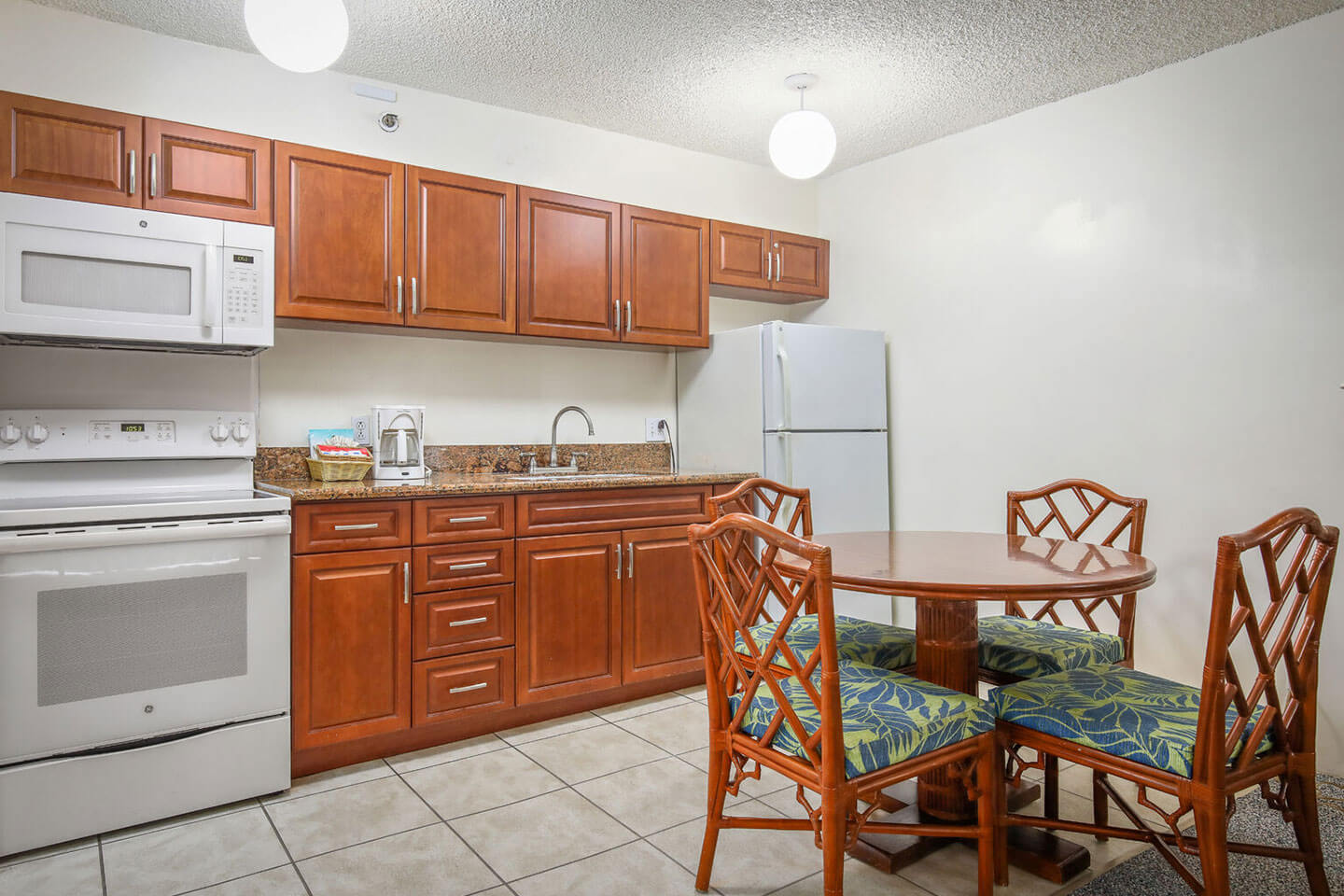 Kitchen with a refrigerator, microwave, stove, ove, sink, and dining area.
