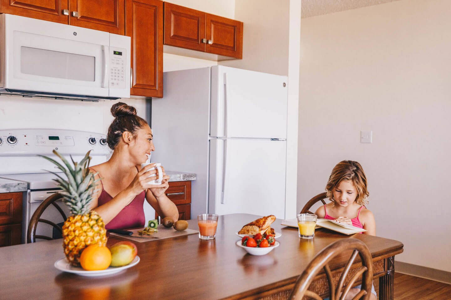 Mother and daughter having breakfast of juice at dining table.