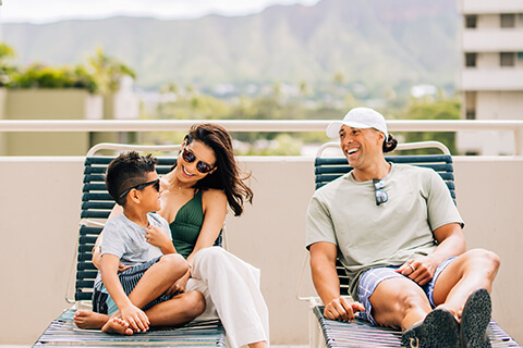 Family relaxing on loungers on deck with mountain views in the background.