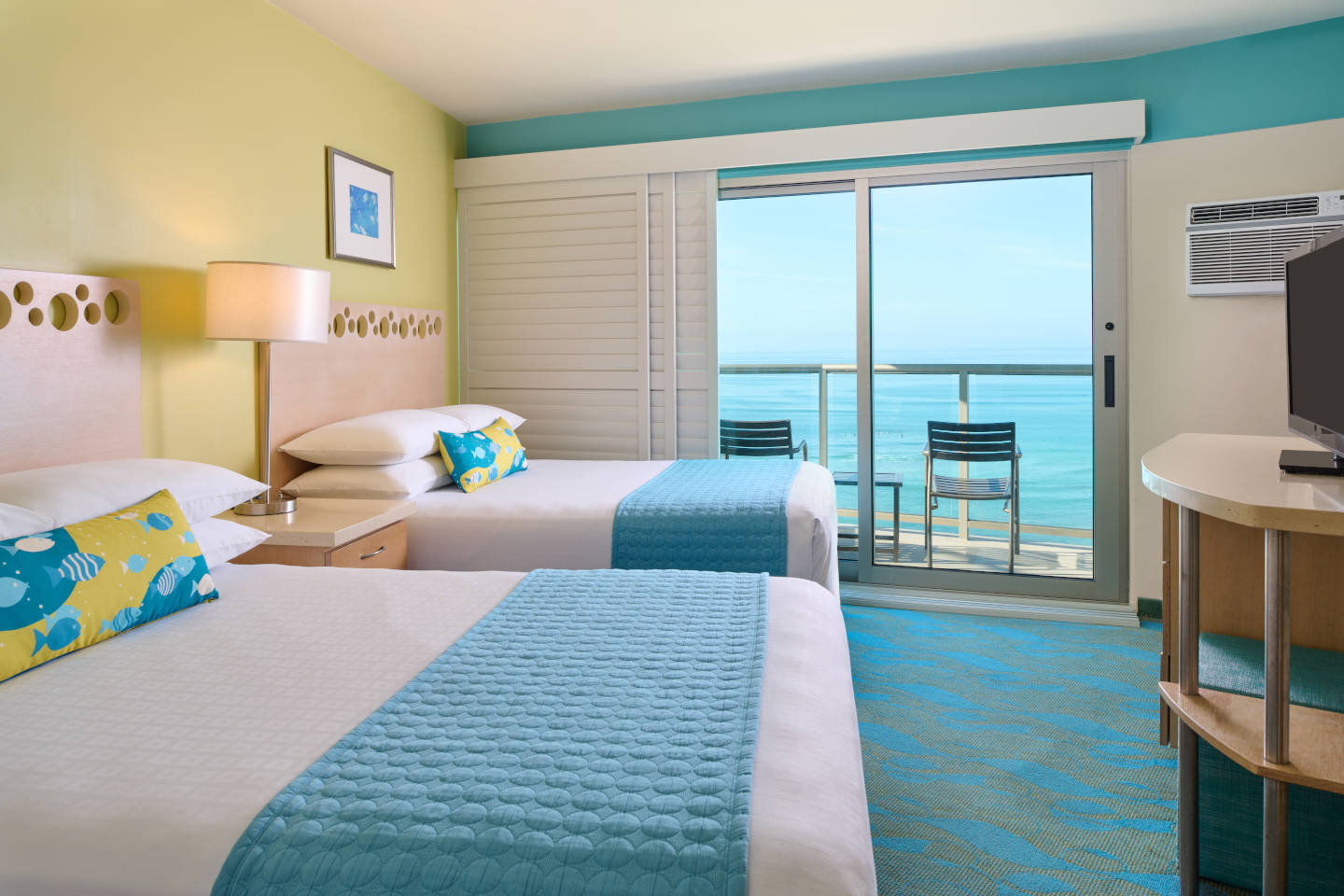 Room with 2 beds, TV, and balcony with oceanfront view.