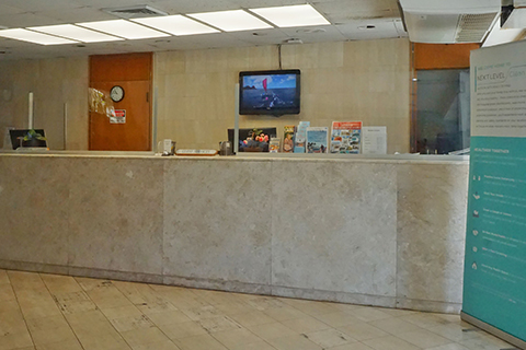 Front desk area with comfortable chairs, tropical plants, and a decorative framed Hawaiian quilt hanging on the wall
