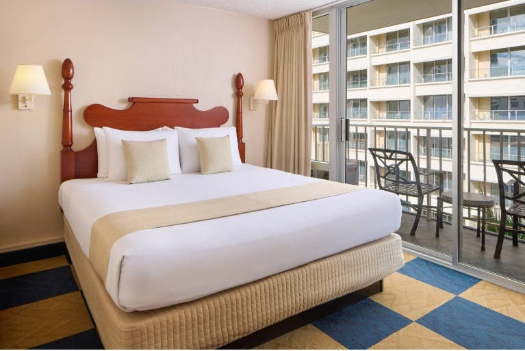 King bed in a two bedroom suite with a sliding glass door leading to a balcony
