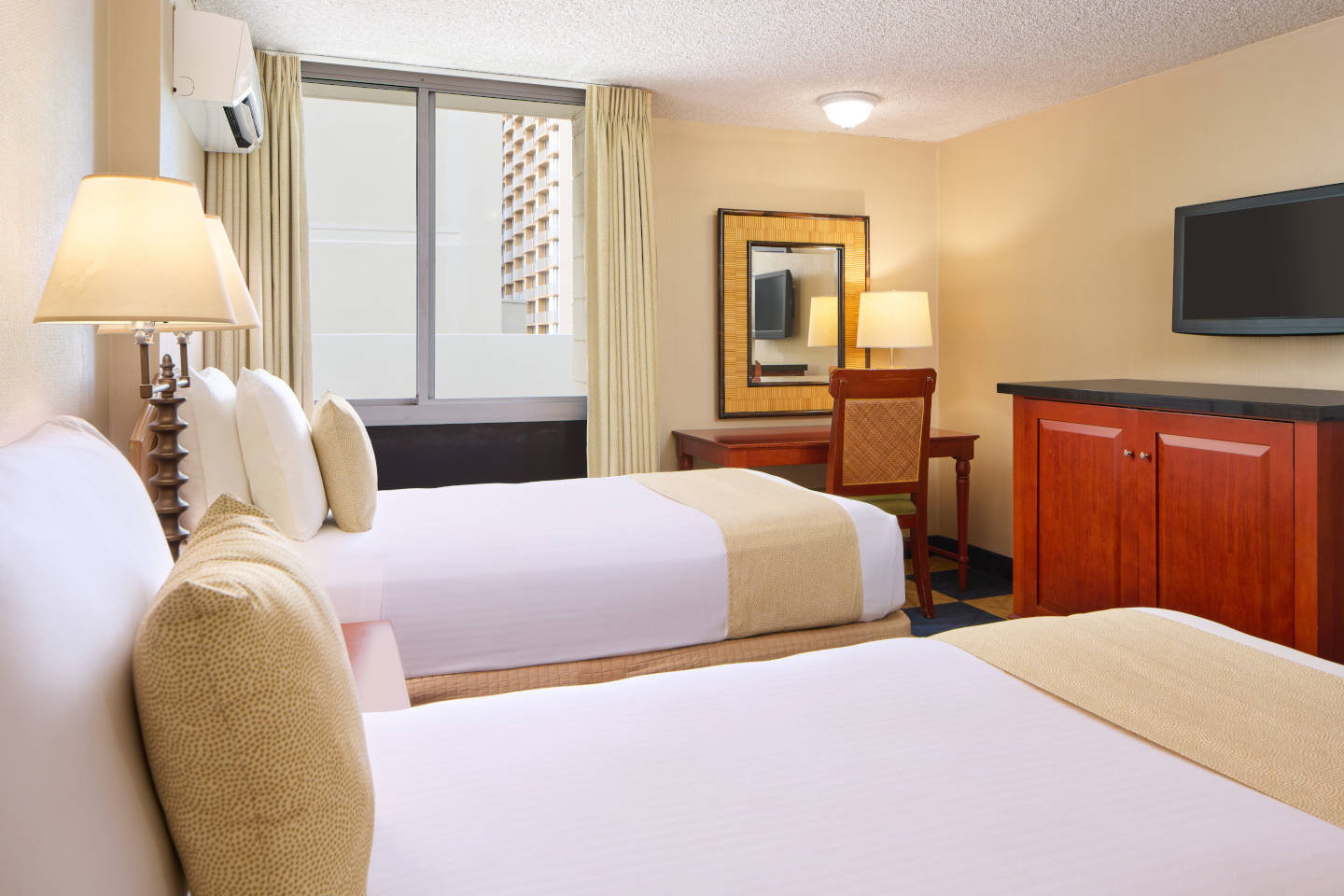 Room with 2 beds, lamps, TV, desk.