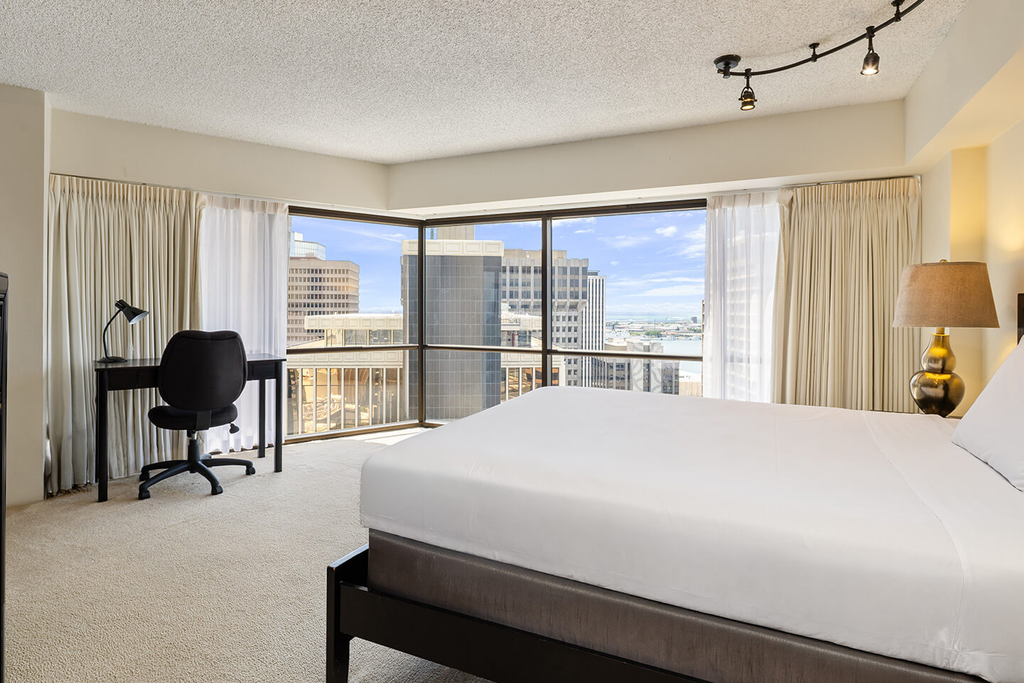 Bedding, seating area, and large picture window.