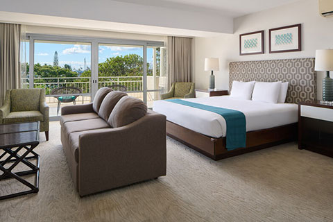Room with bed, night stand, lamps, couch, balcony.