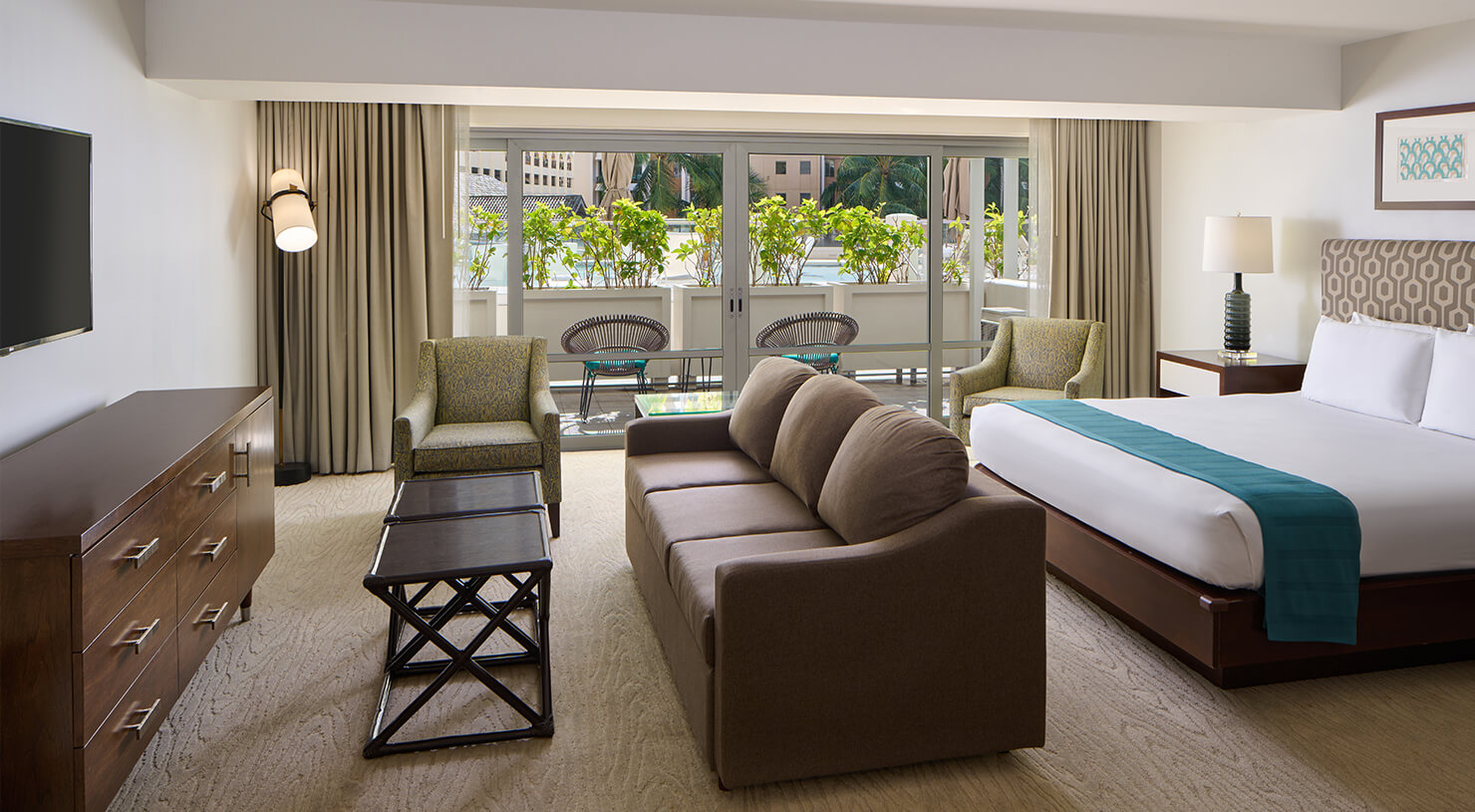 Room with bed, couch, TV, lamps, and balcony.