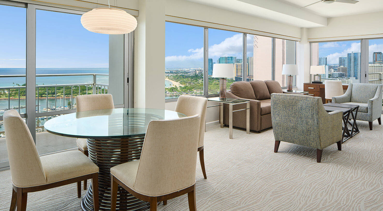 Living area with dining table, couch, chairs, large picture windows. and balcony.