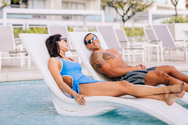 Couple relaxing in pool loungers.