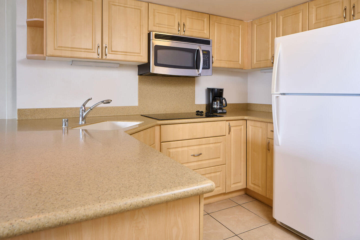 Kitchen with refrigerator, stove, microwave, sink, counters, and cabinets.