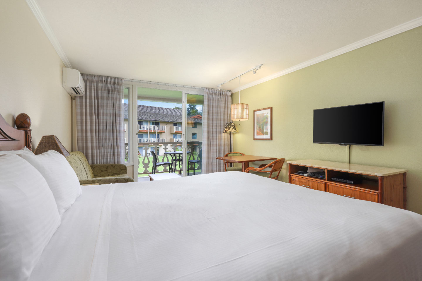 Room with a bed, couch, TV, dining area, and patio.