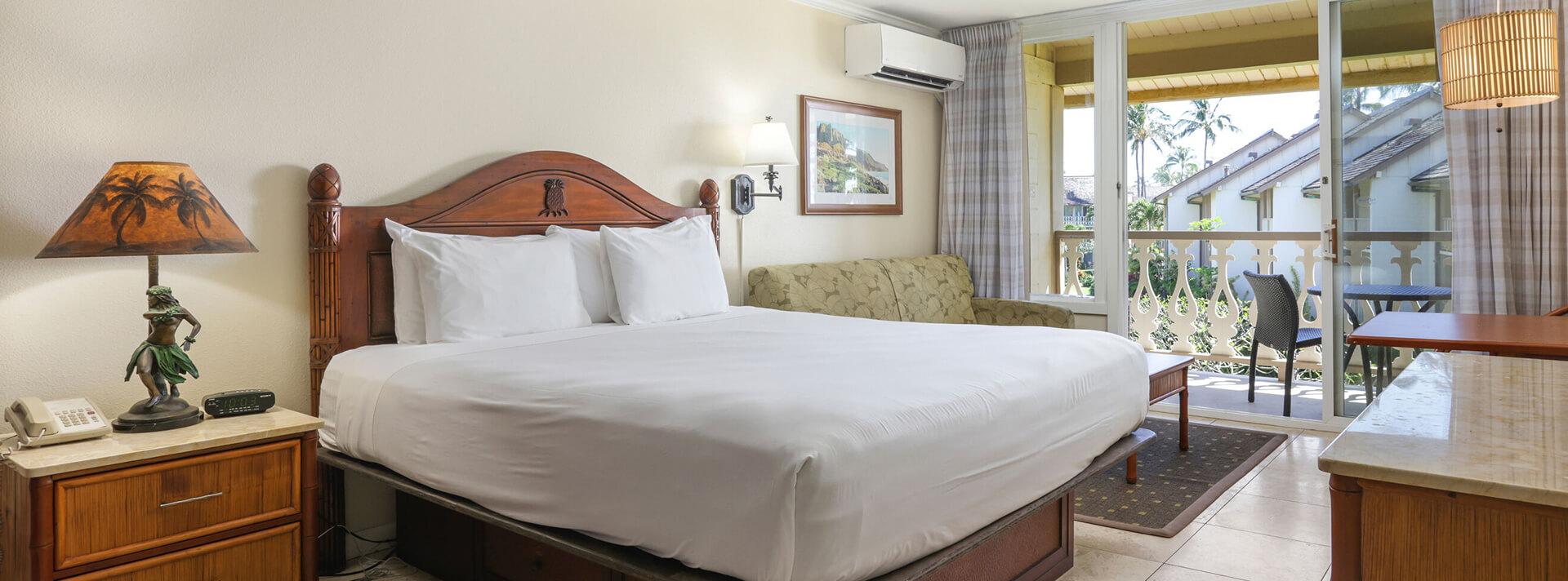 Room with bed, nightstands, lamps, couch, table, chairs, balcony, ocean view