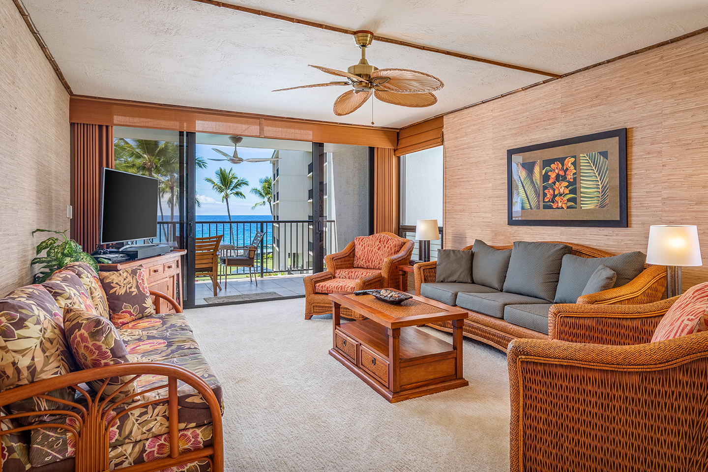 Living area with a couch, coffee table, TV, lamps, and balcony.