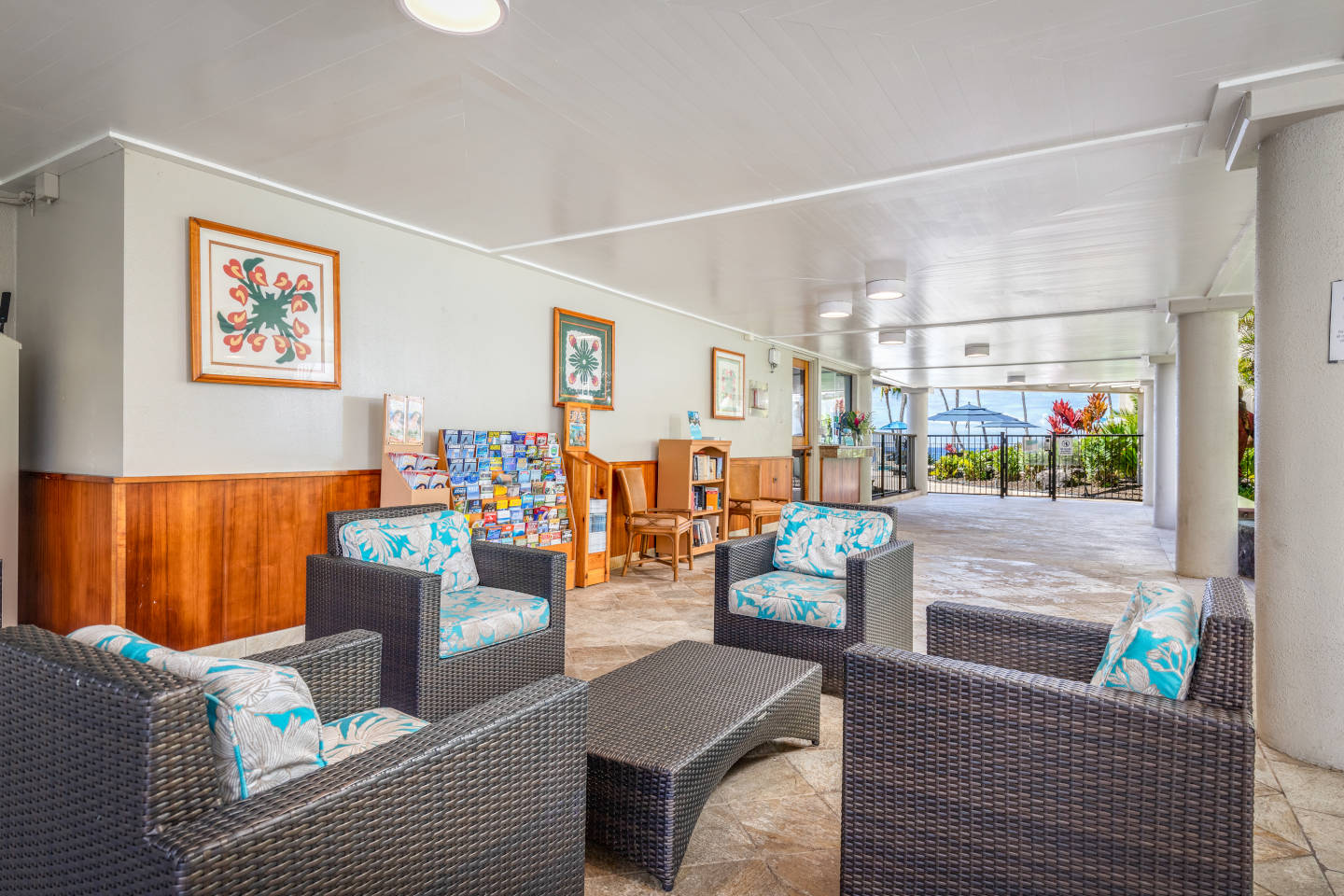 Lobby with floral pattern cushion chairs and a matching table surrounded by tropical plants.