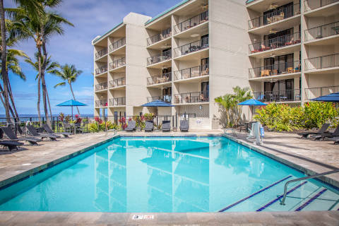 View from the pool deck looking at the pool's edge with lounge chairs and umbrella poolside
