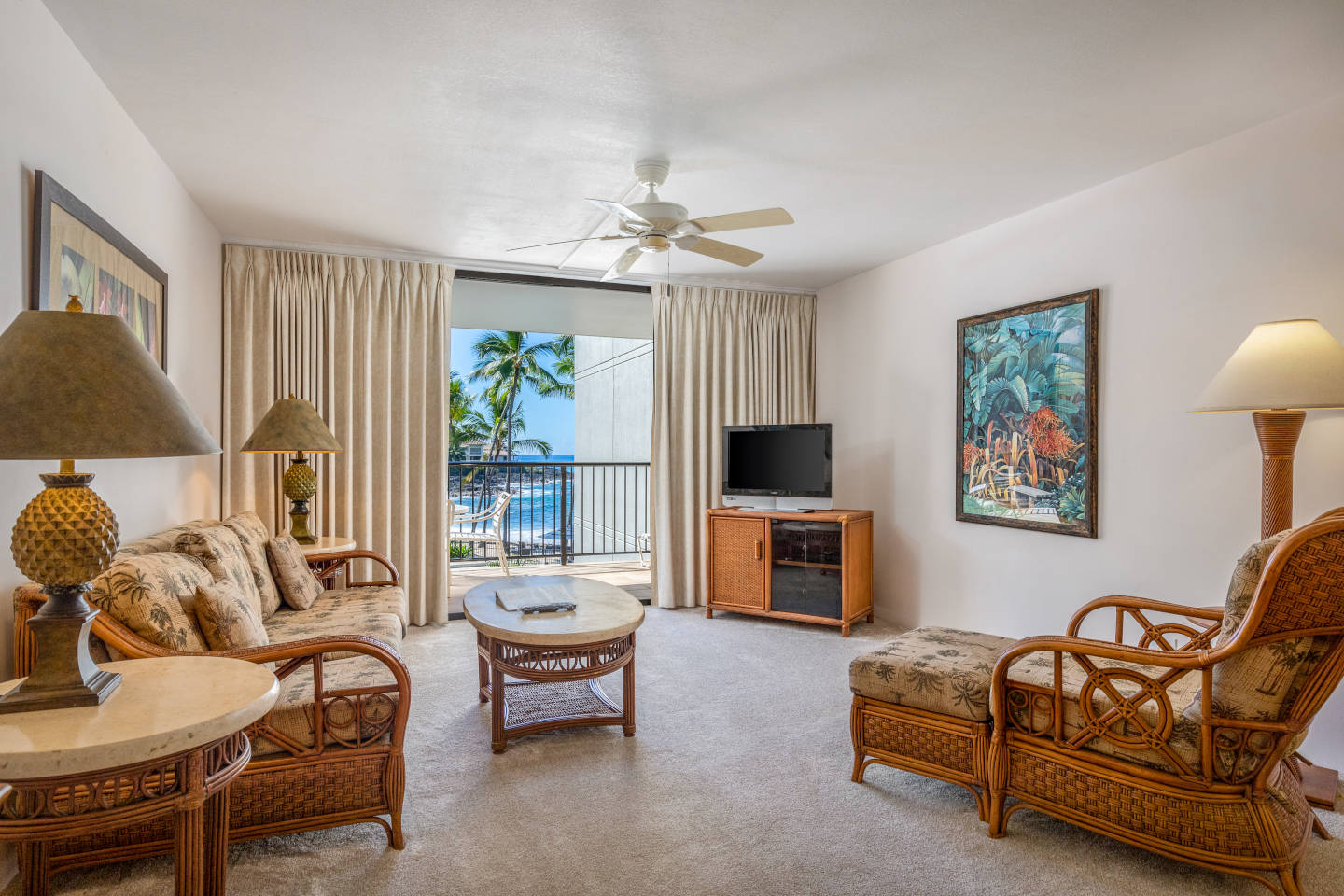 Living area with a couch, coffee table, TV, lamps, and balcony.
