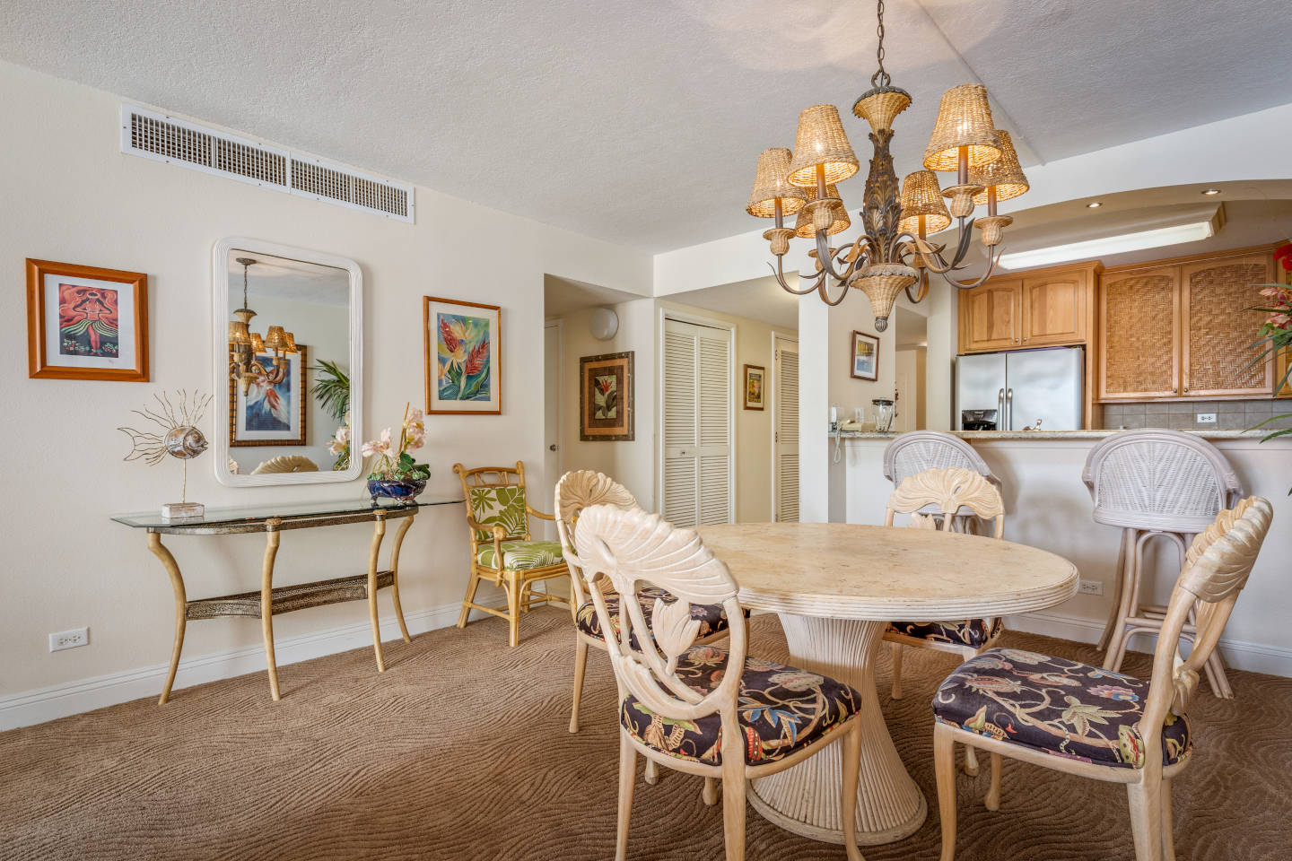 Dining area with dining table, chairs, mirror and a side table, bar stools facing the kitchen.