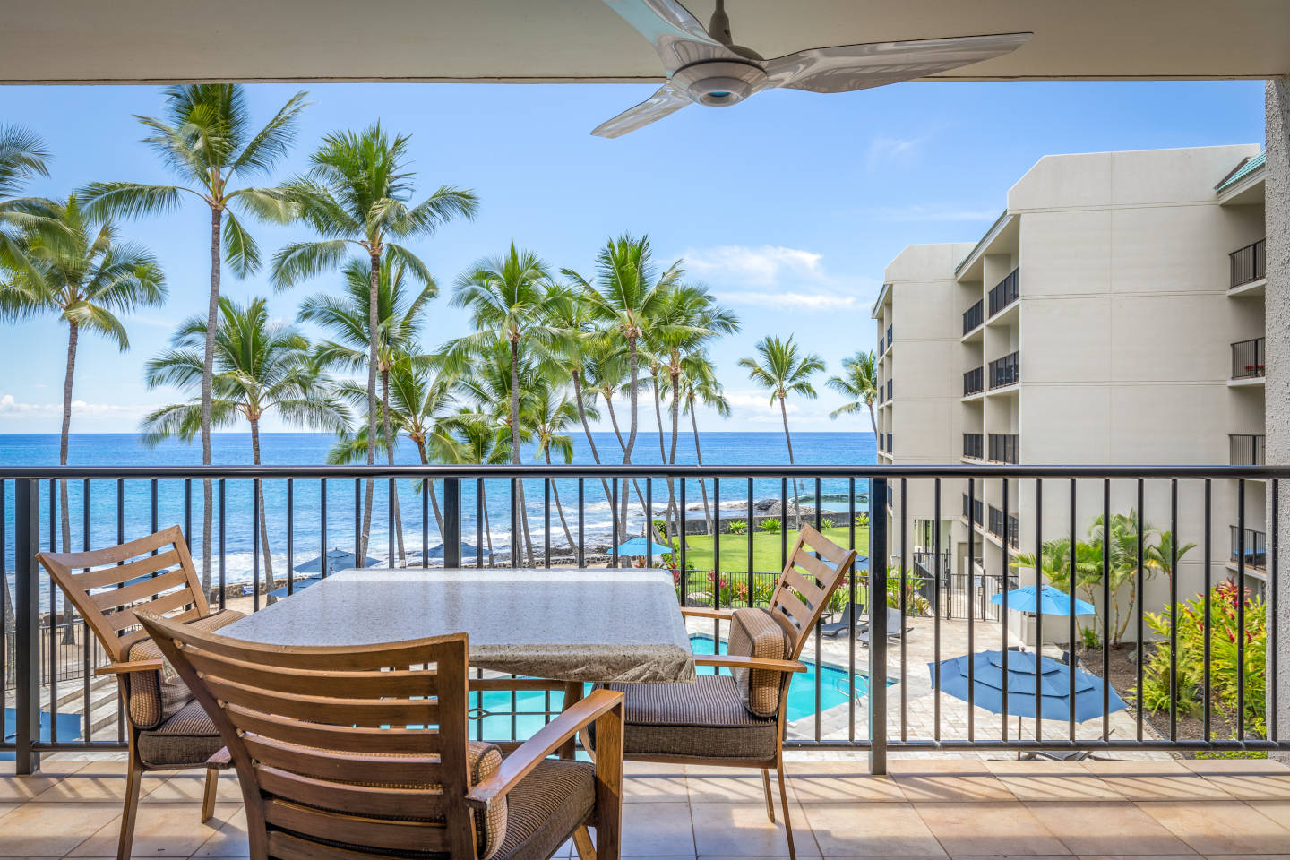 Balcony overlooking pool and oceanfront. Table and chairs.