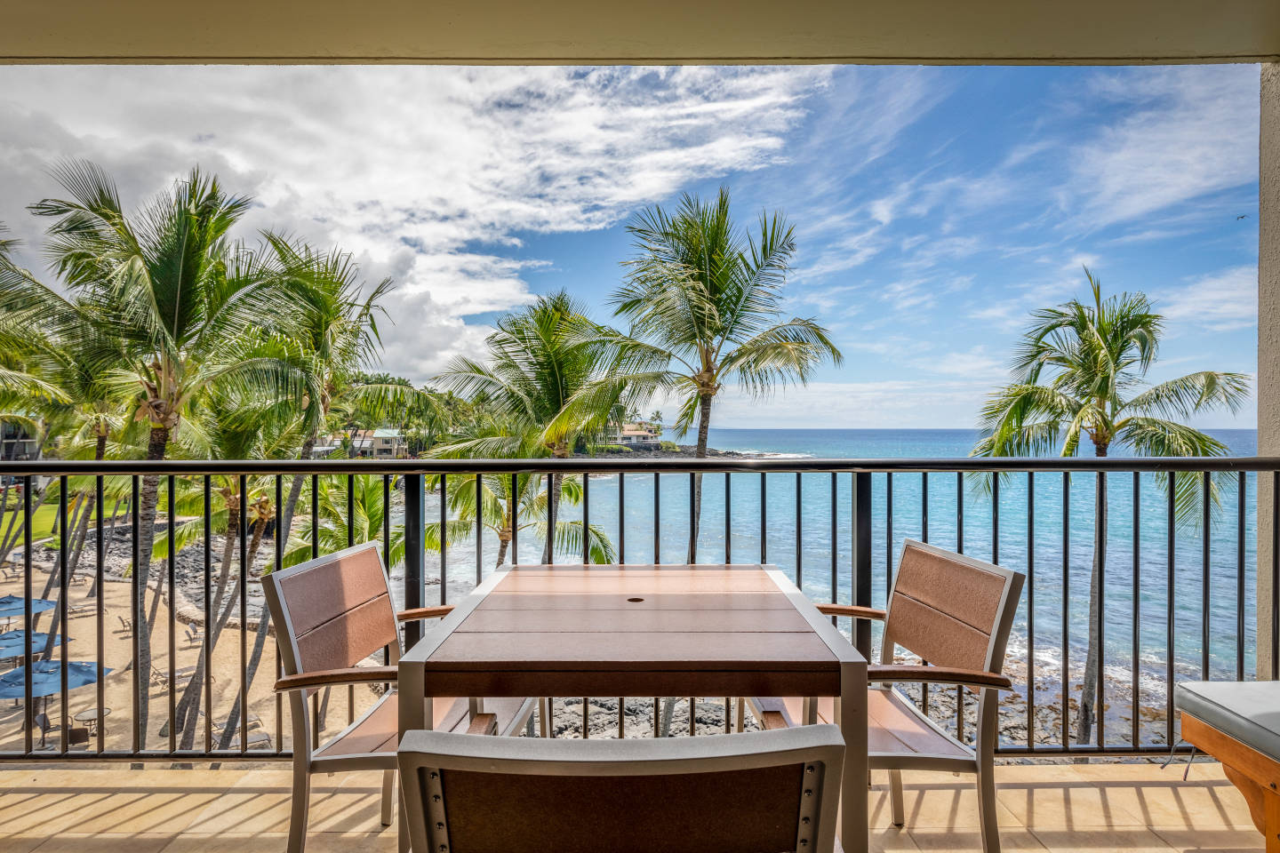 Balcony with table, chairs, and view overlooking the beach.