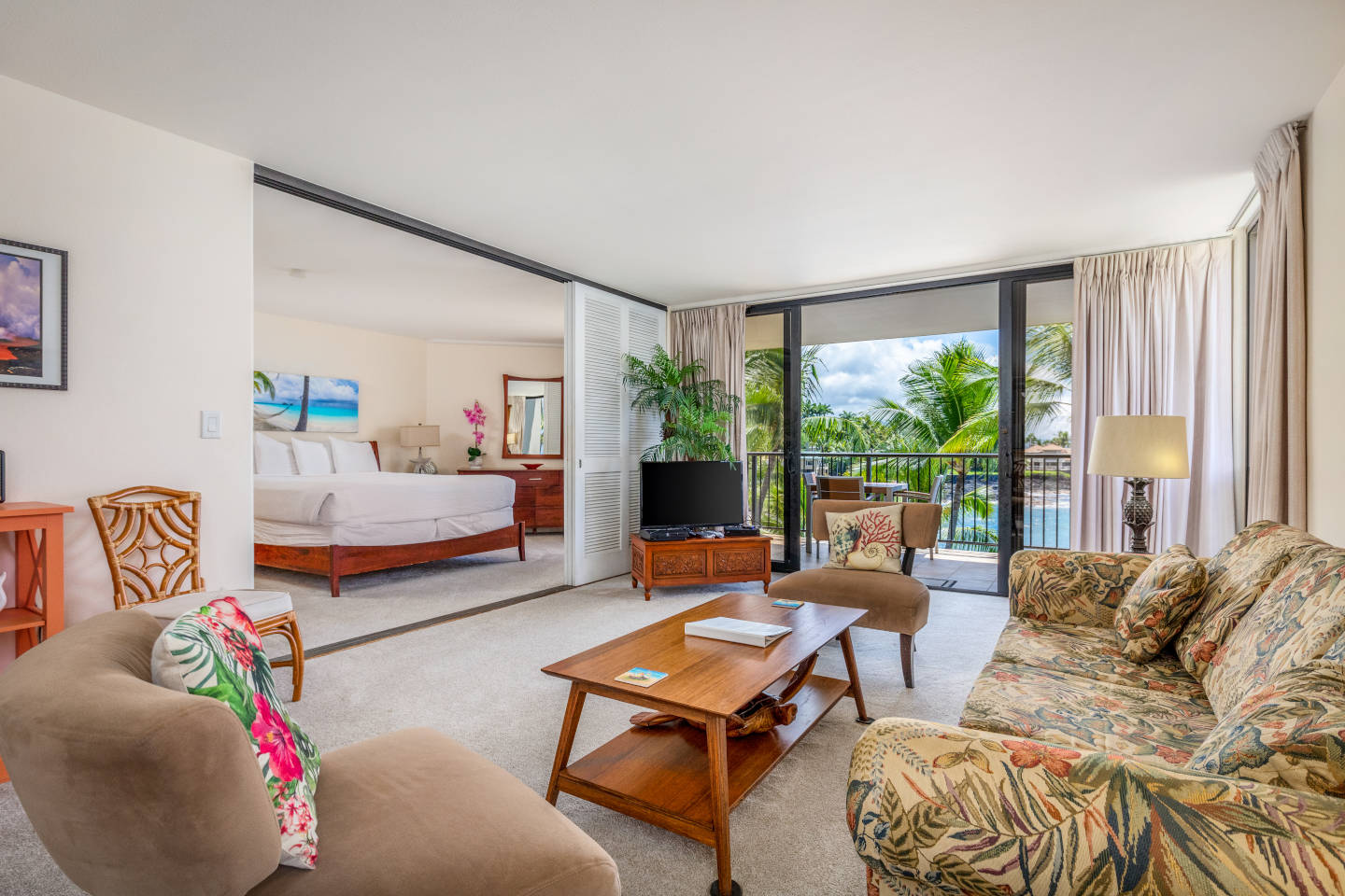 Living room with sofa, coffee table, sliding doors that open to the bedroom and a view of ocean.