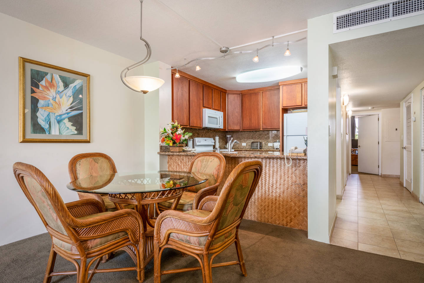 Dining area with a table and chairs, kitchen in background.