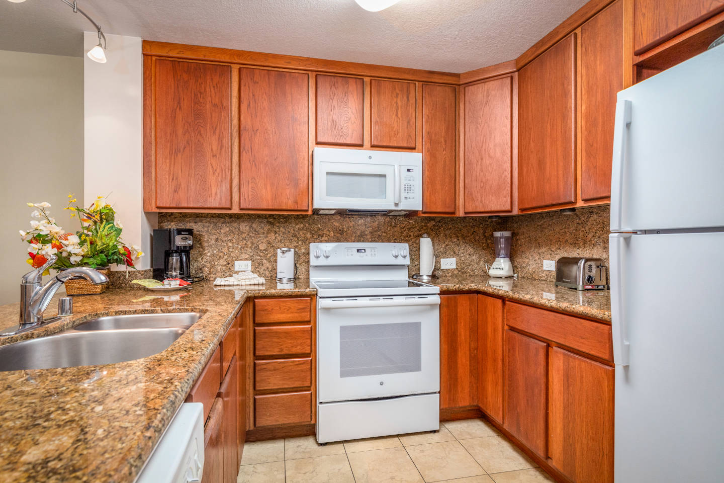 Kitchen with refrigerator, stove, microwave, sink, counters, and cabinets.