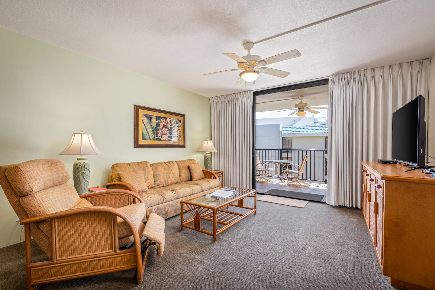 Living room with couch, coffee table, TV, balcony.