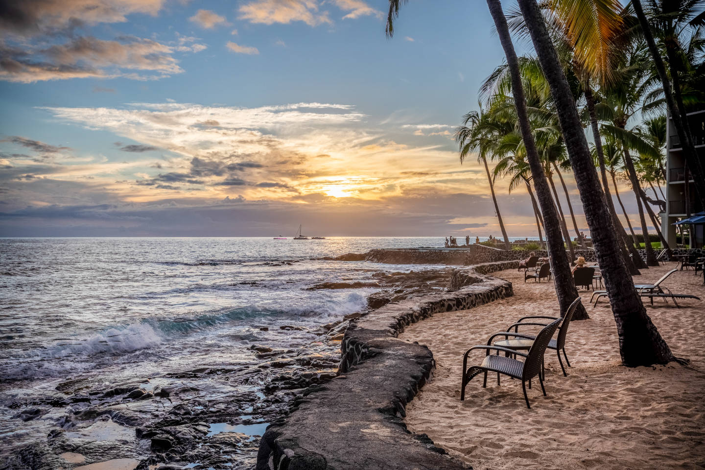 View of a beautiful orange lite sky as the sun sets in the horizon from the sand chair area near the shoreline.