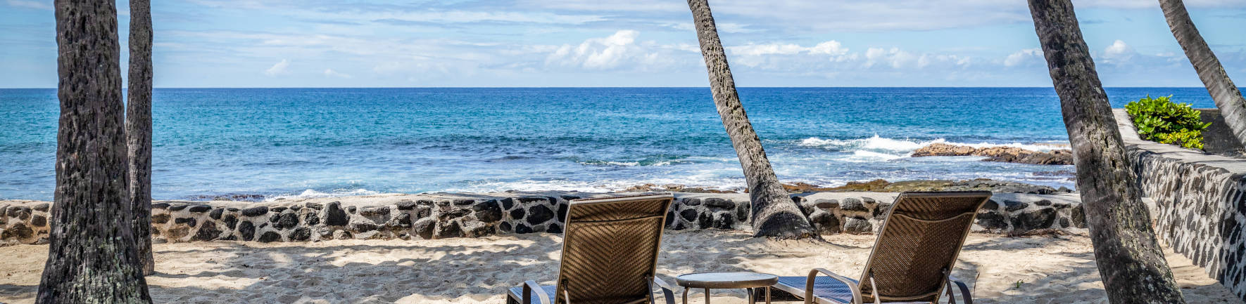View of the ocean near the shoreline in the sand chair area under the coconut trees